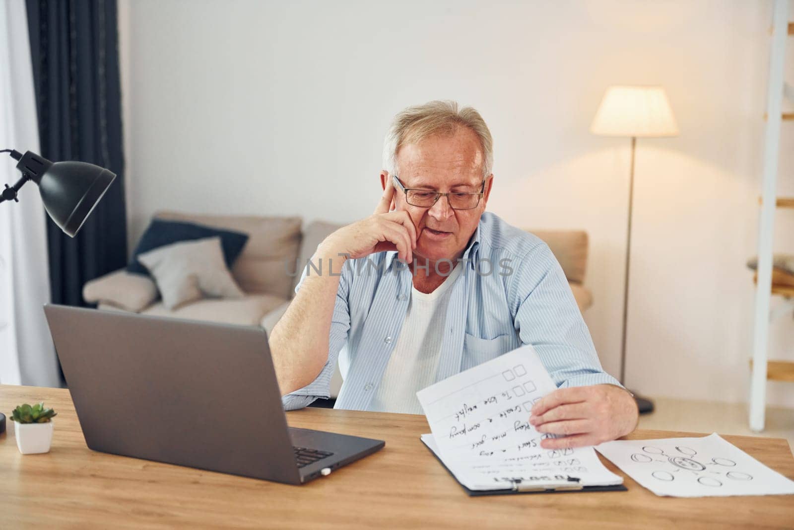 Working by using laptop. Senior man in nice clothes is at home.