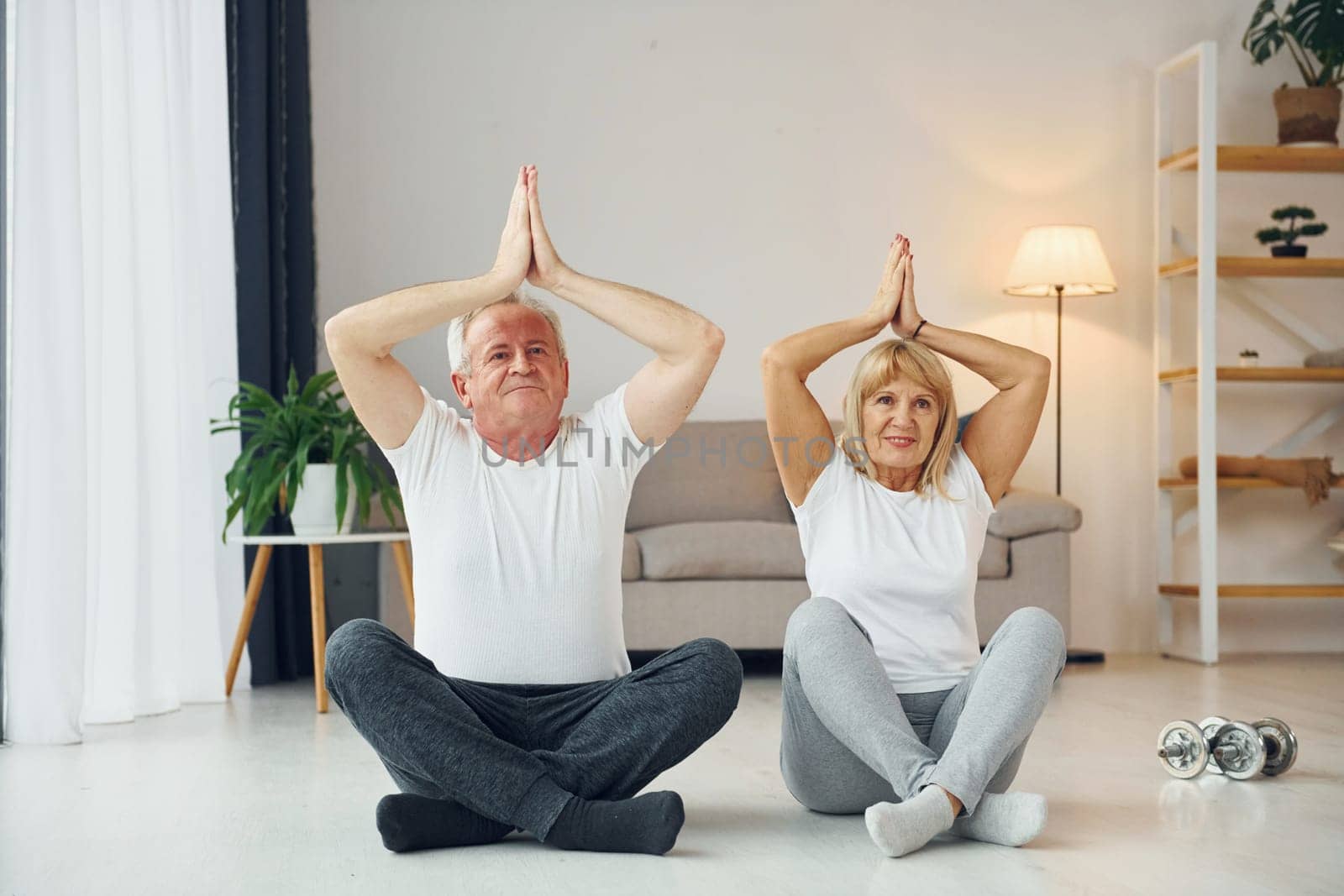 Doing yoga. Senior man and woman is together at home by Standret