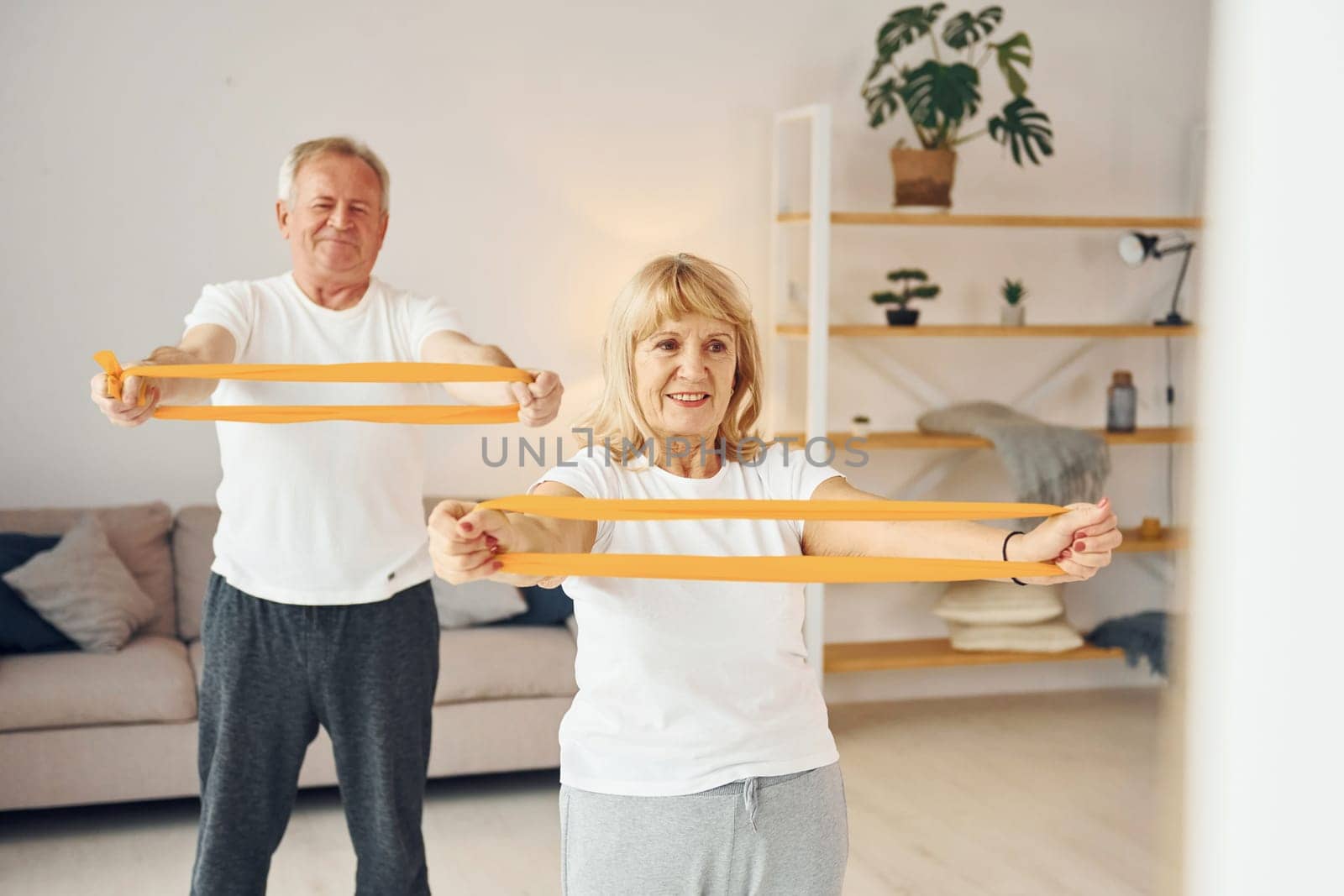 Doing stretching and fitness exercises. Senior man and woman is together at home.