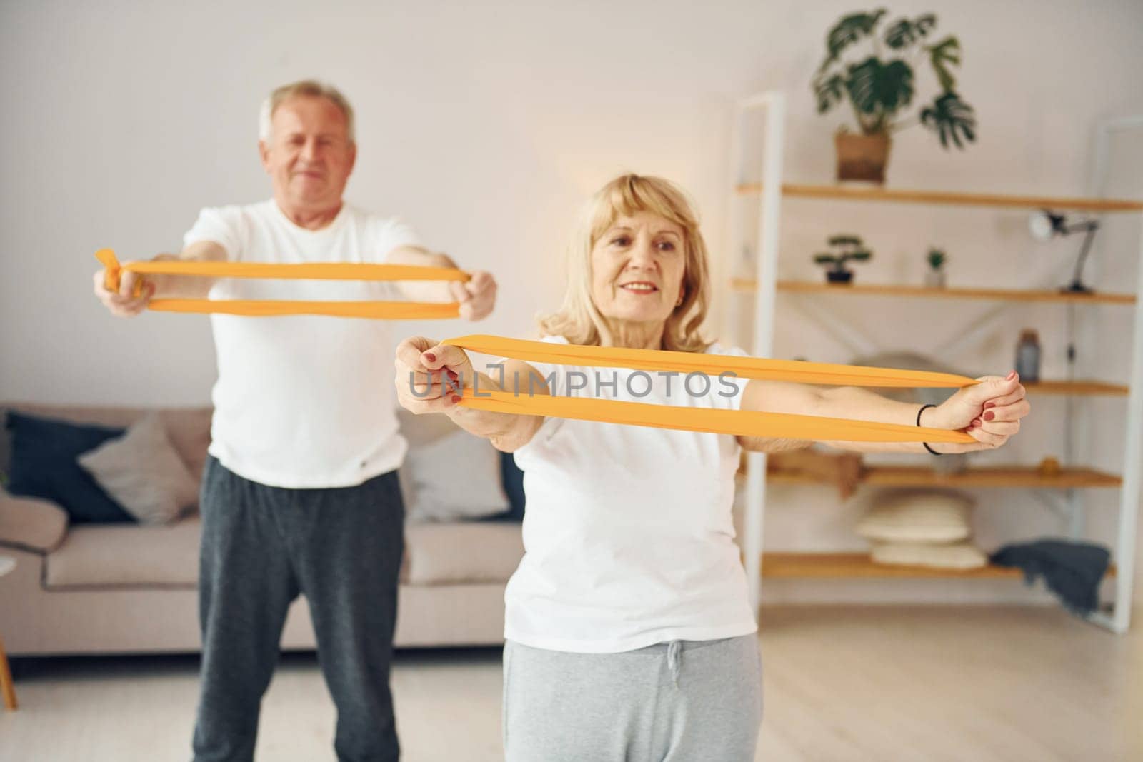 Doing stretching and fitness exercises. Senior man and woman is together at home.
