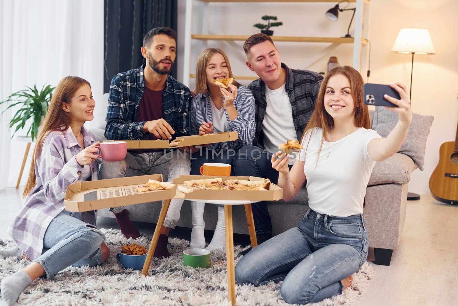 Woman making selfie. Group of friends have party indoors together.