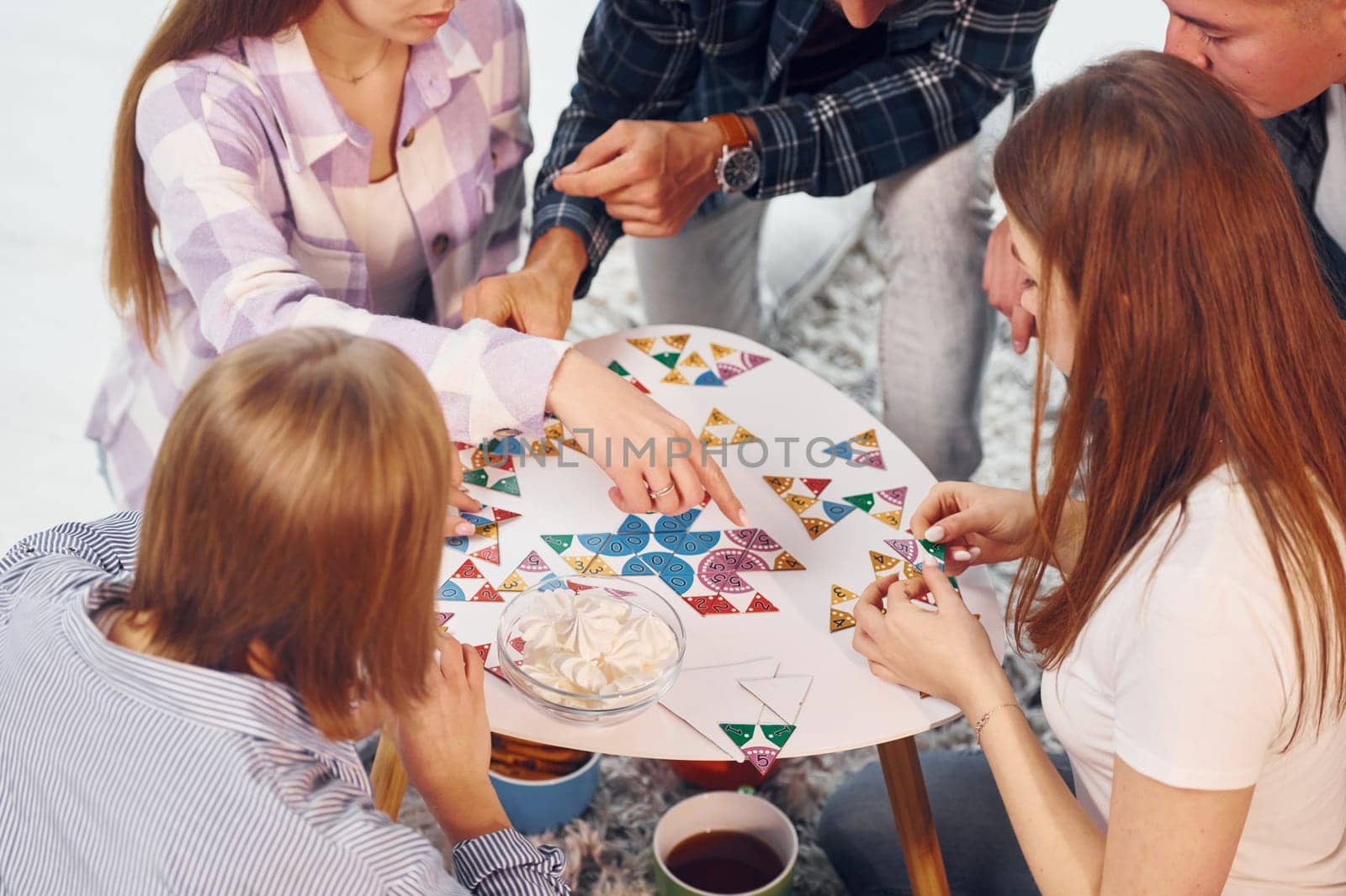 Playing puzzle game. Group of friends have party indoors together.