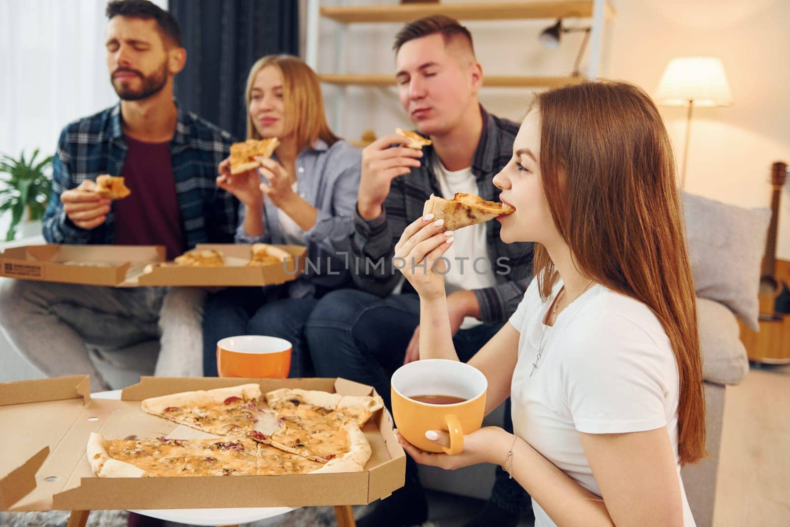 It's pizza time. Group of friends have party indoors together.