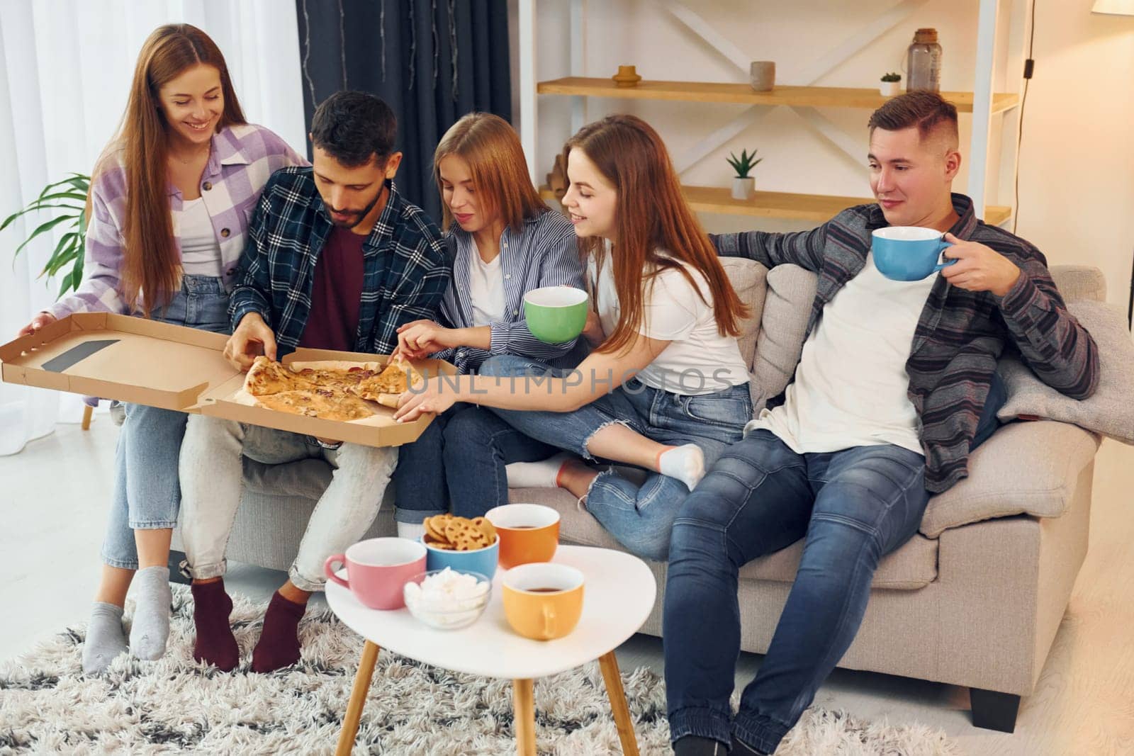 Eating food and drinking tea. Group of friends have party indoors together.