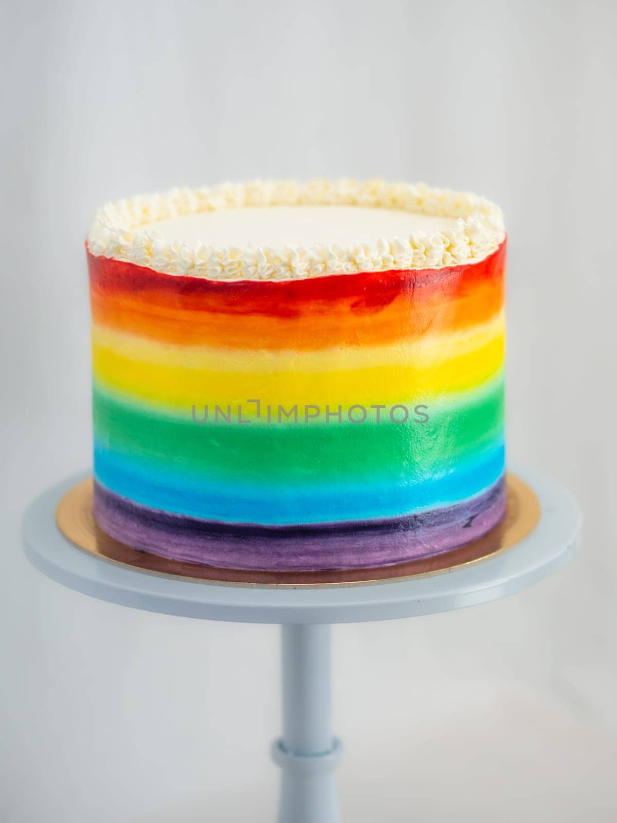 pastry chef working on a frosted cup cake with lgbt rainbow colours for wedding union party celebration. Birthday cupcake. Rainbow paper cup liners. Happy Birthday. Celebration Holidays. LGBT pride.
