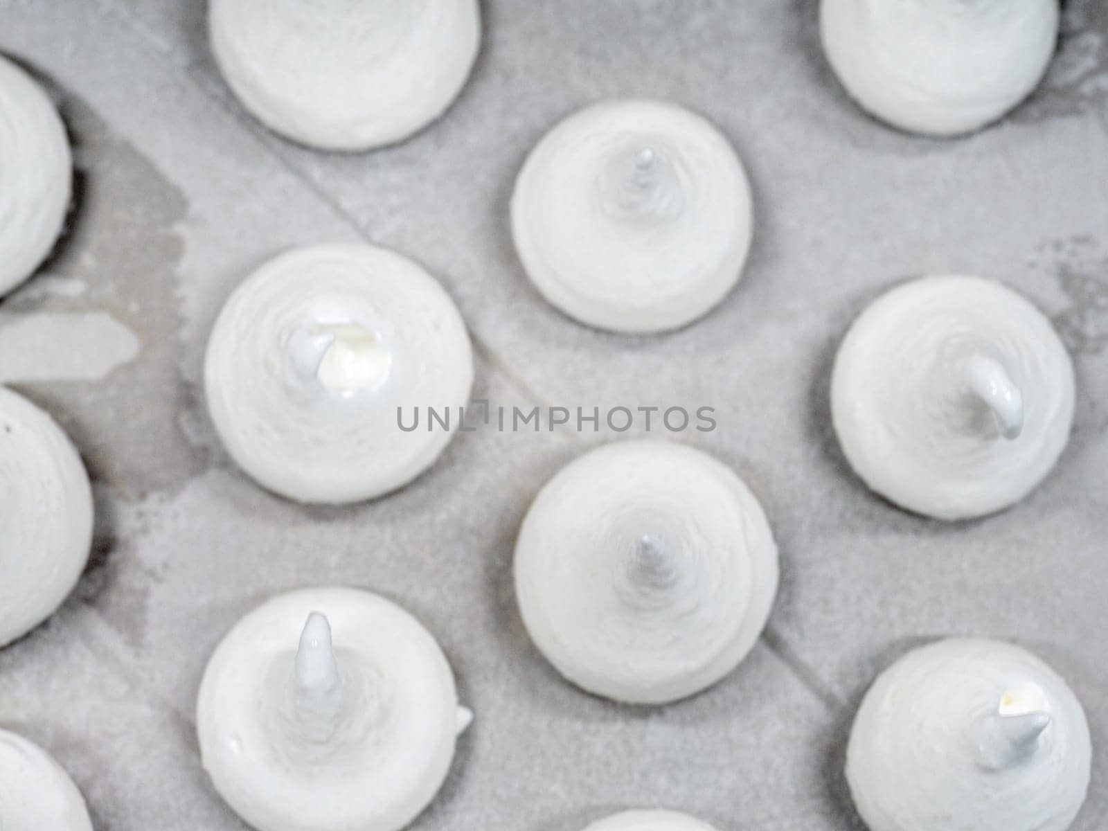 pastry chef baker artisan making white swirl and twirl meringue cones with piping bag filled with egg cream and sugar to bake for sweet preparation