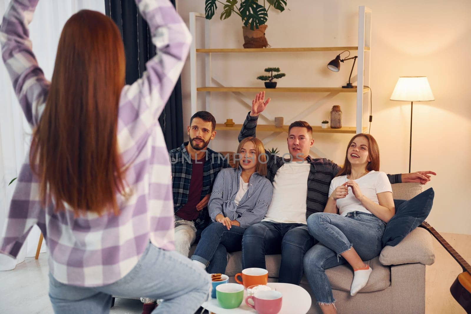 Playing game with using body language and poses. Group of friends have party indoors together.