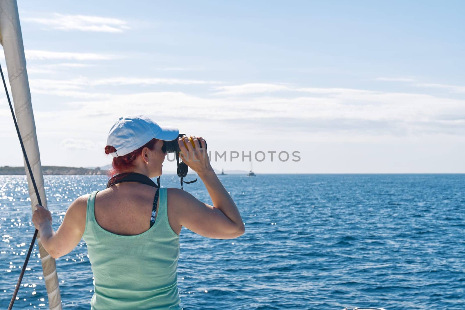 Girl on a yacht looking through binoculars. Happy female captain looks through a binoculars by PhotoTime