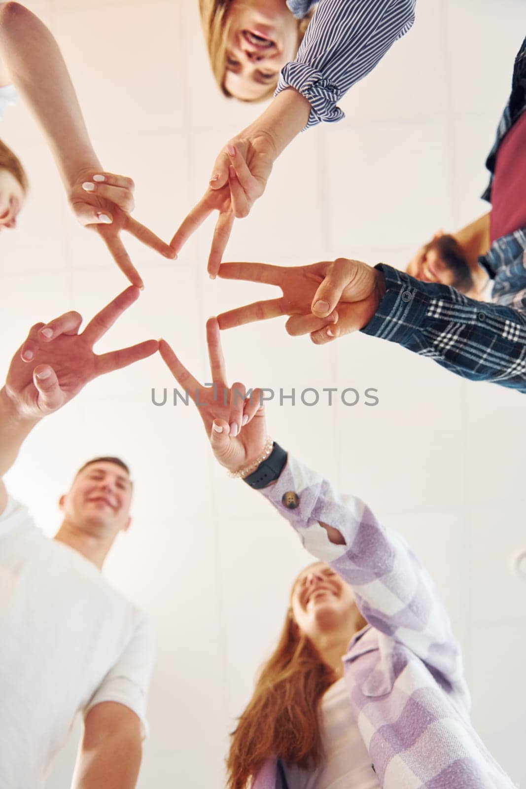 Making gesture by hands. Group of friends standing together by Standret
