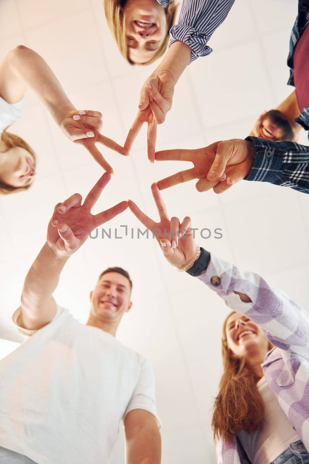 Making gesture by hands. Group of friends standing together by Standret
