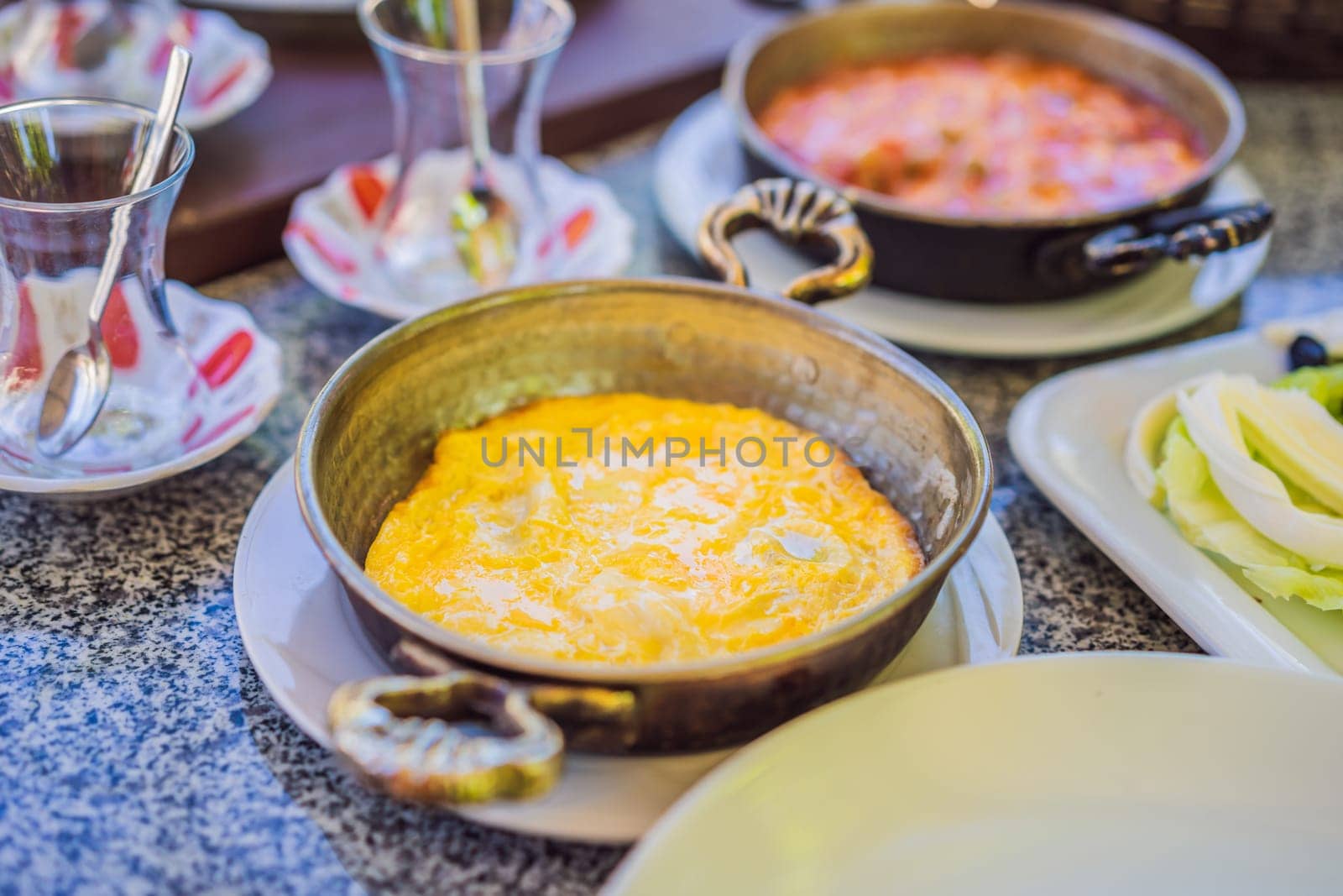 Turkish breakfast table. Pastries, vegetables, greens, olives, cheeses, fried eggs, spices, jams, honey, tea in copper pot and tulip glasses, wide composition by galitskaya