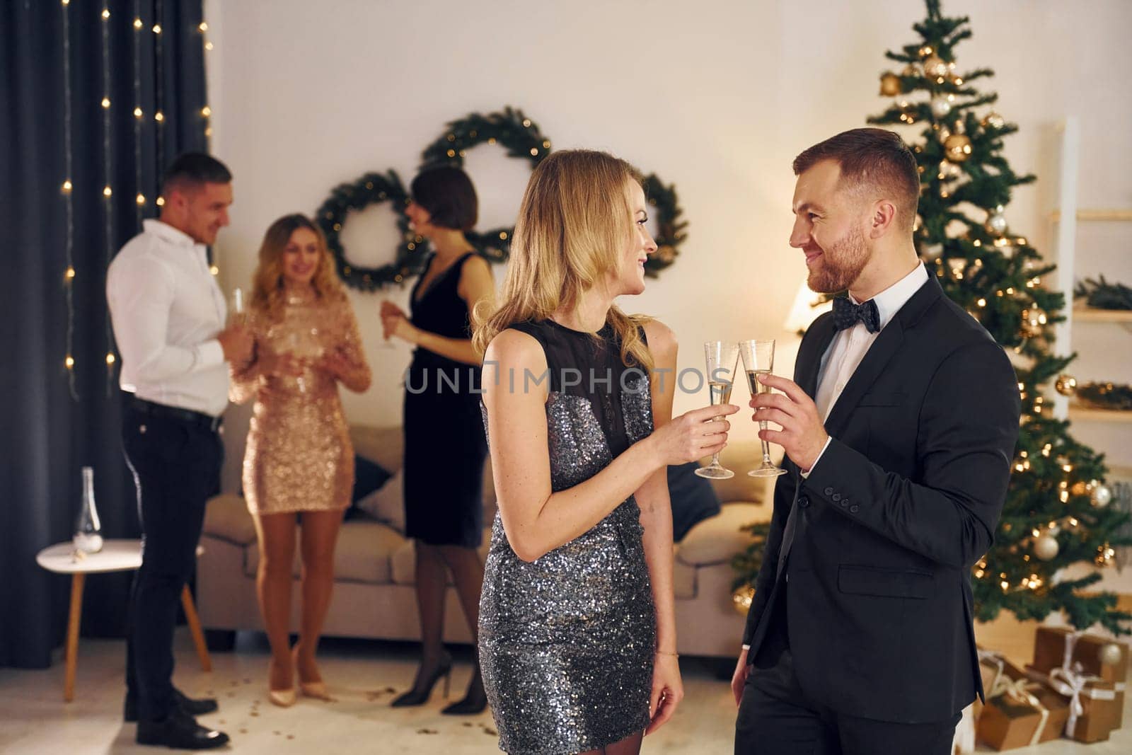 Beautiful couple. Group of people have a new year party indoors together by Standret