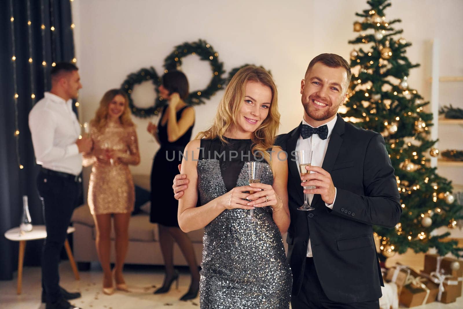 Beautiful couple. Group of people have a new year party indoors together.