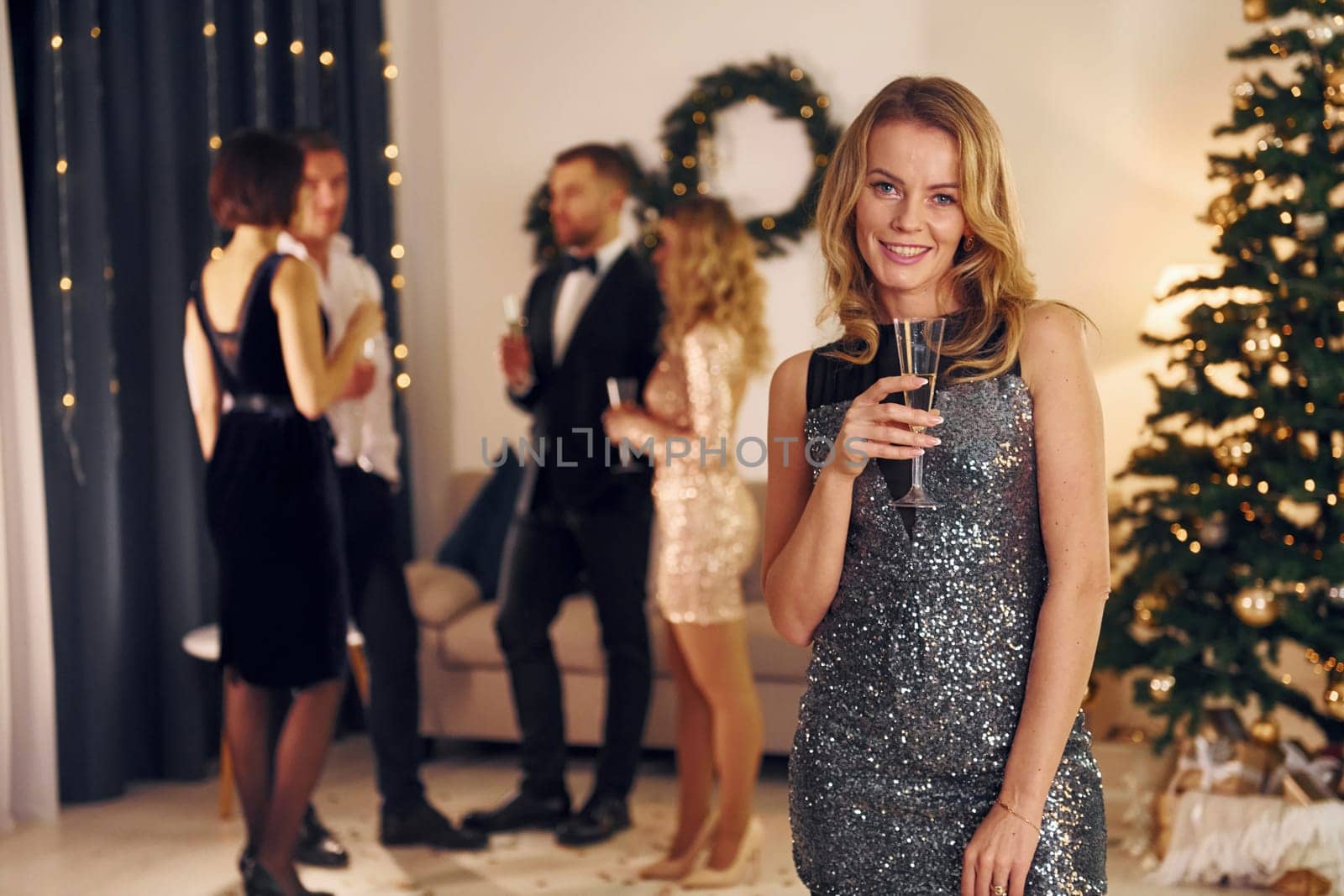 Woman is in the front of her friends. Group of people have a new year party indoors together.