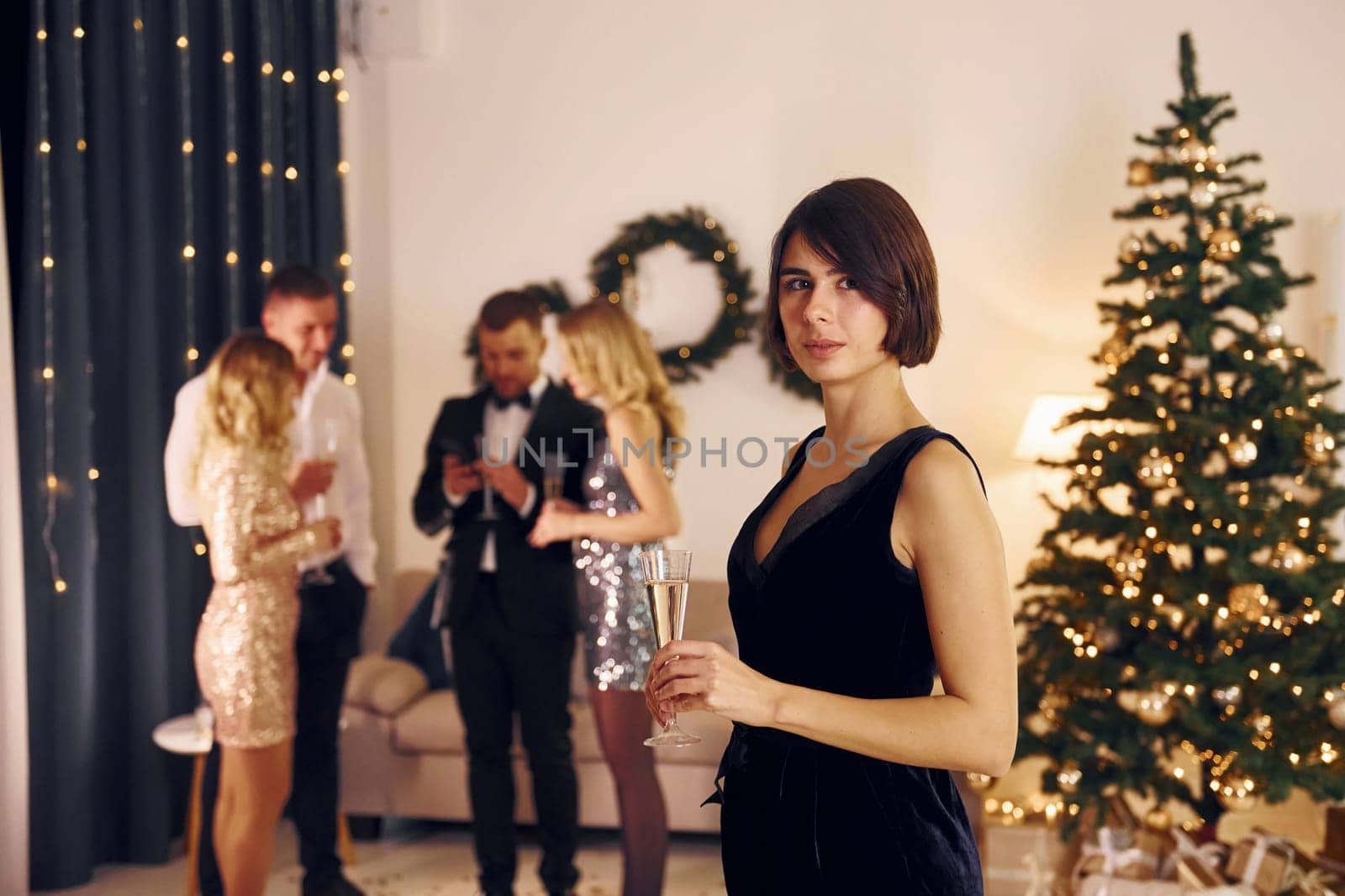 Woman standing in front of her friends. Group of people have a new year party indoors together.