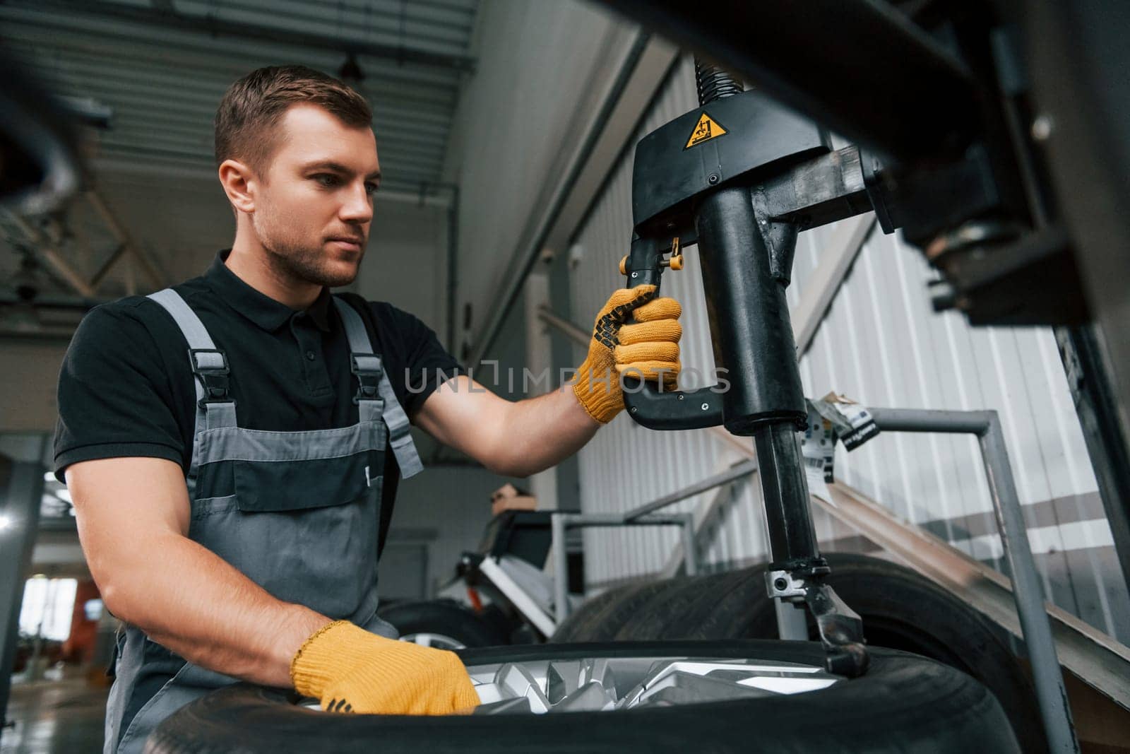 Strong hands. Man in uniform is working in the auto service.