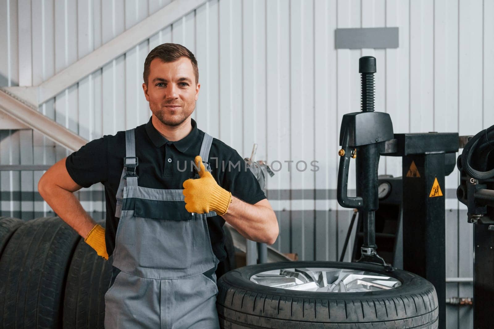 Broken wheel. Man in uniform is working in the auto service.