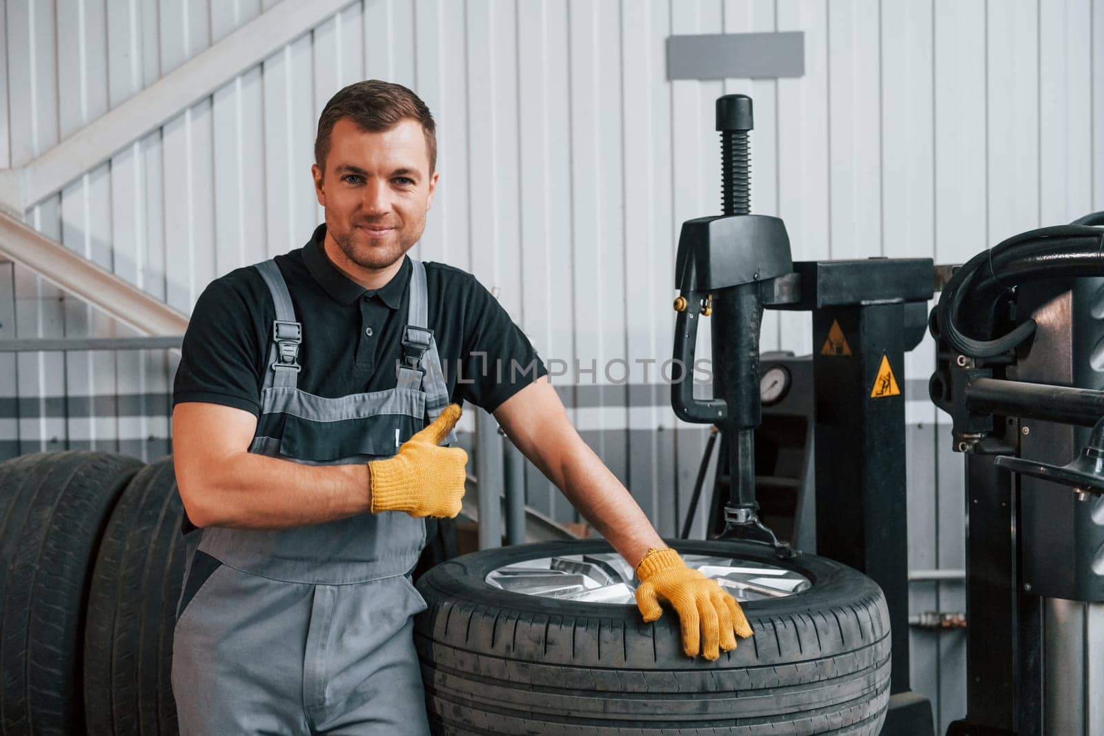 Broken wheel. Man in uniform is working in the auto service.