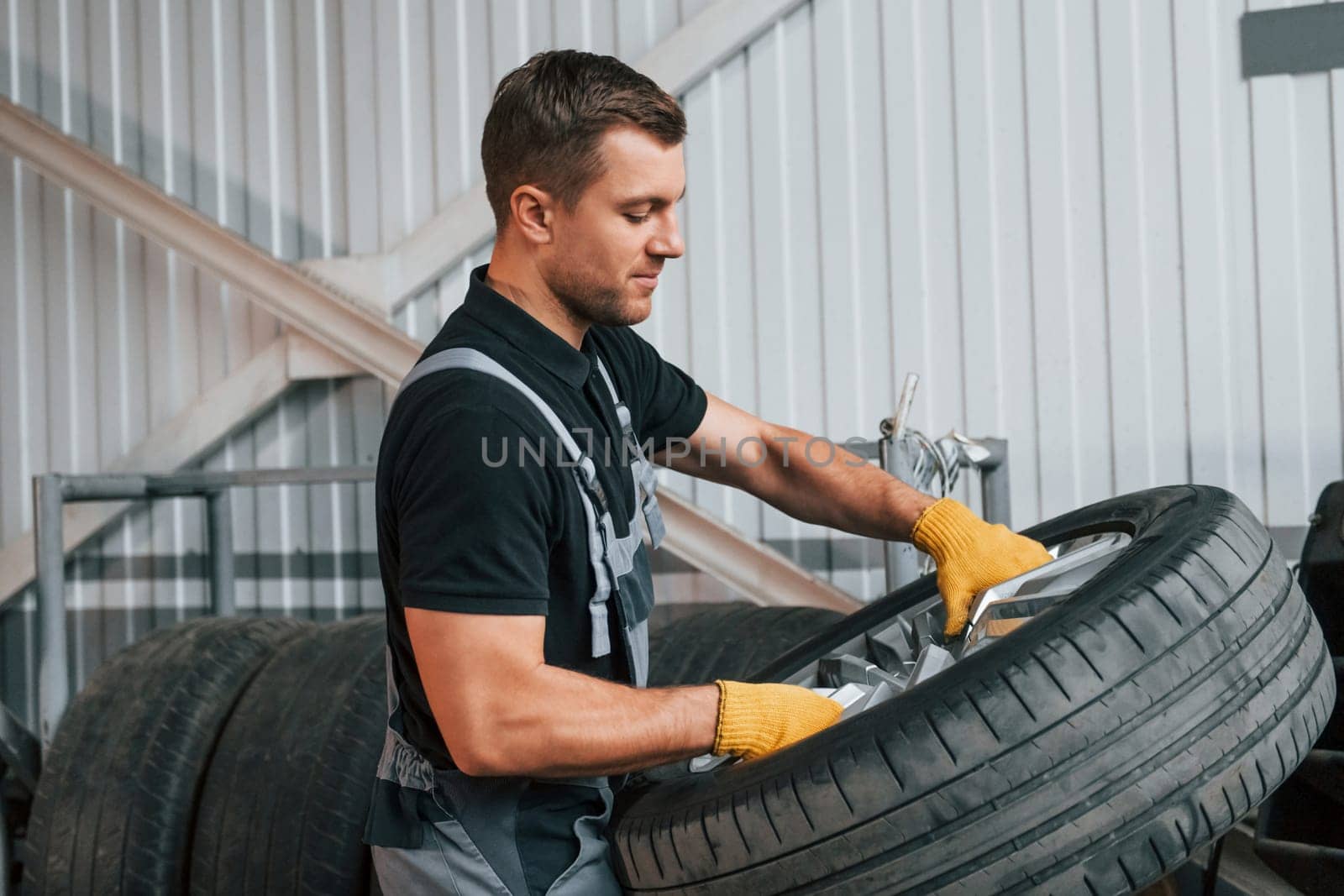 Broken wheel. Man in uniform is working in the auto service.