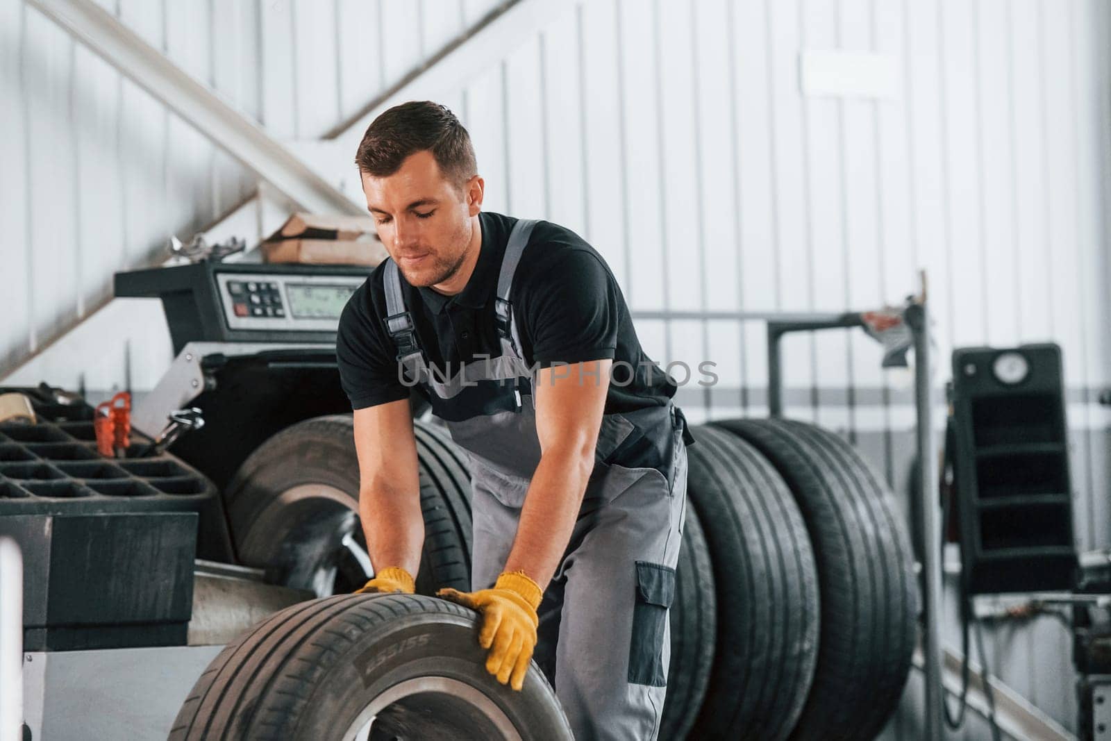 Replacement of the old tire. Man in uniform is working in the auto service.