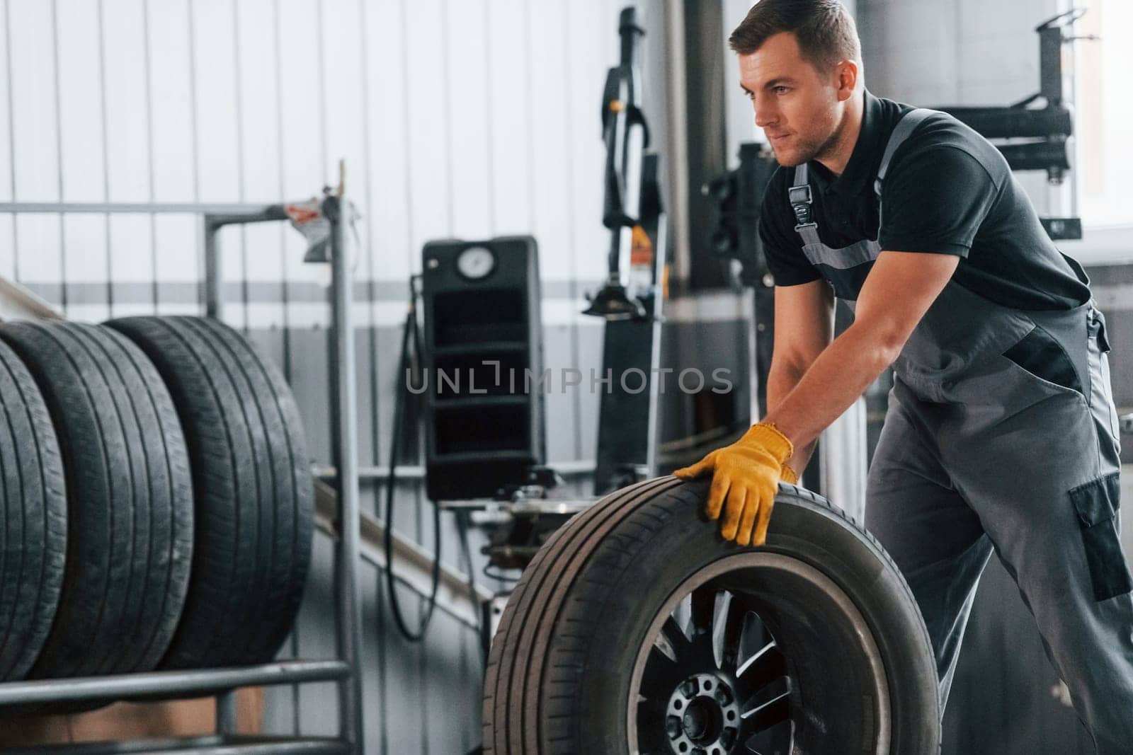 Replacement of the old tire. Man in uniform is working in the auto service.