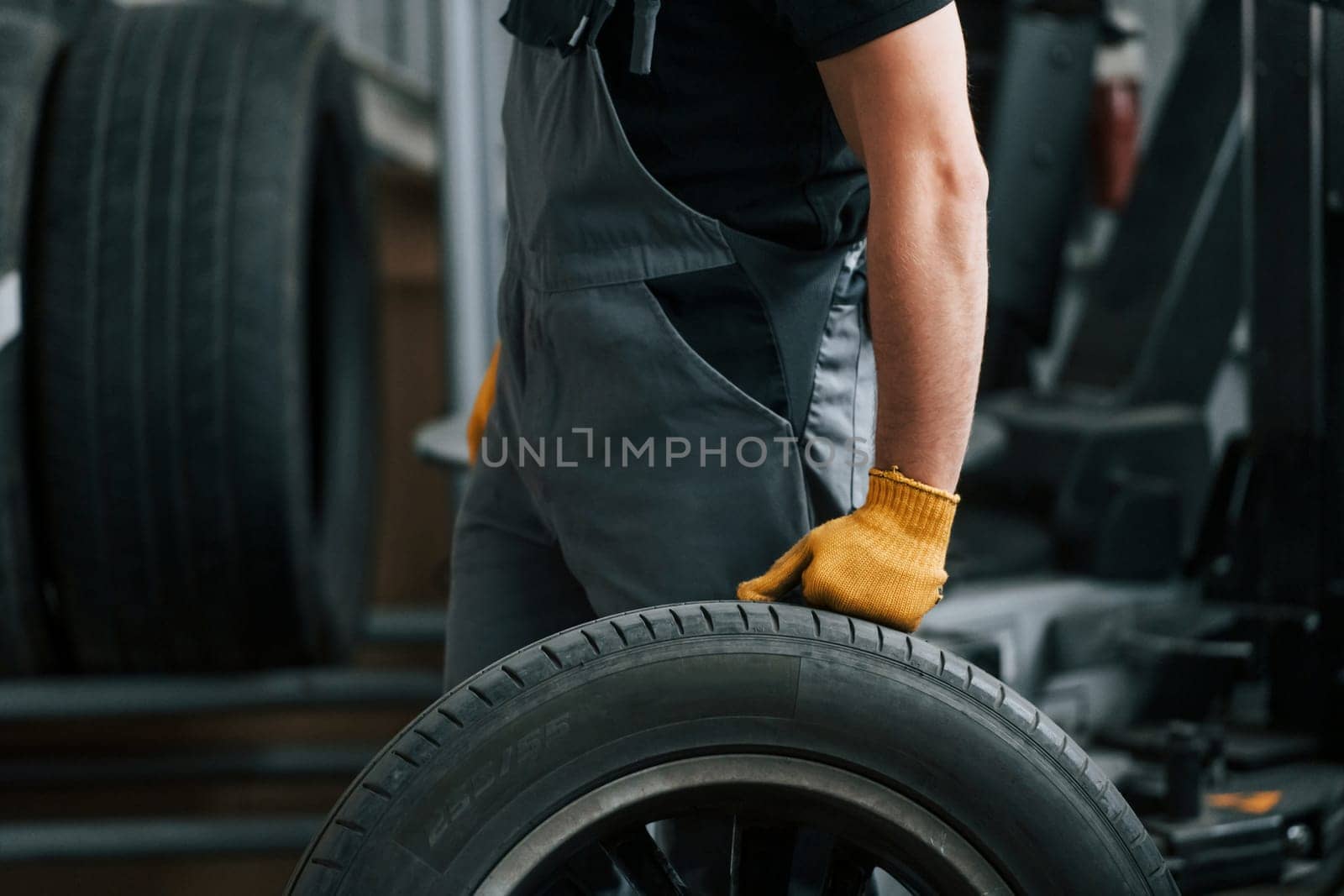 Replacement of the old tire. Man in uniform is working in the auto service.