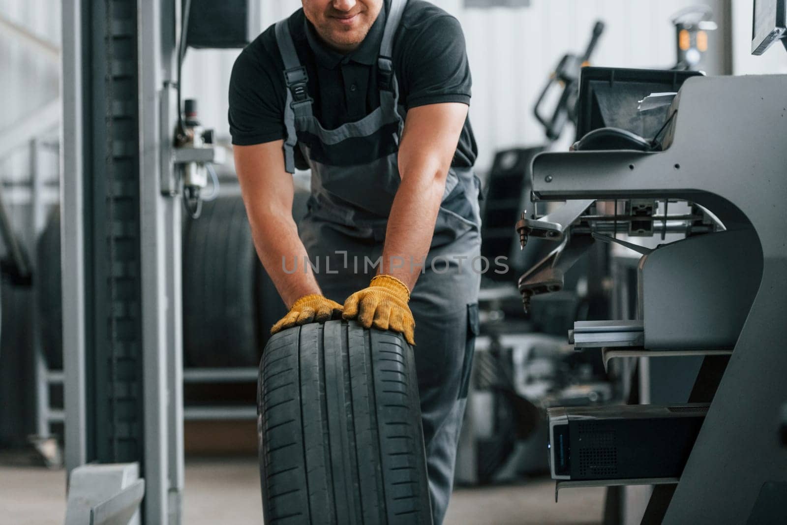 Front view. Man in uniform is working in the auto service by Standret