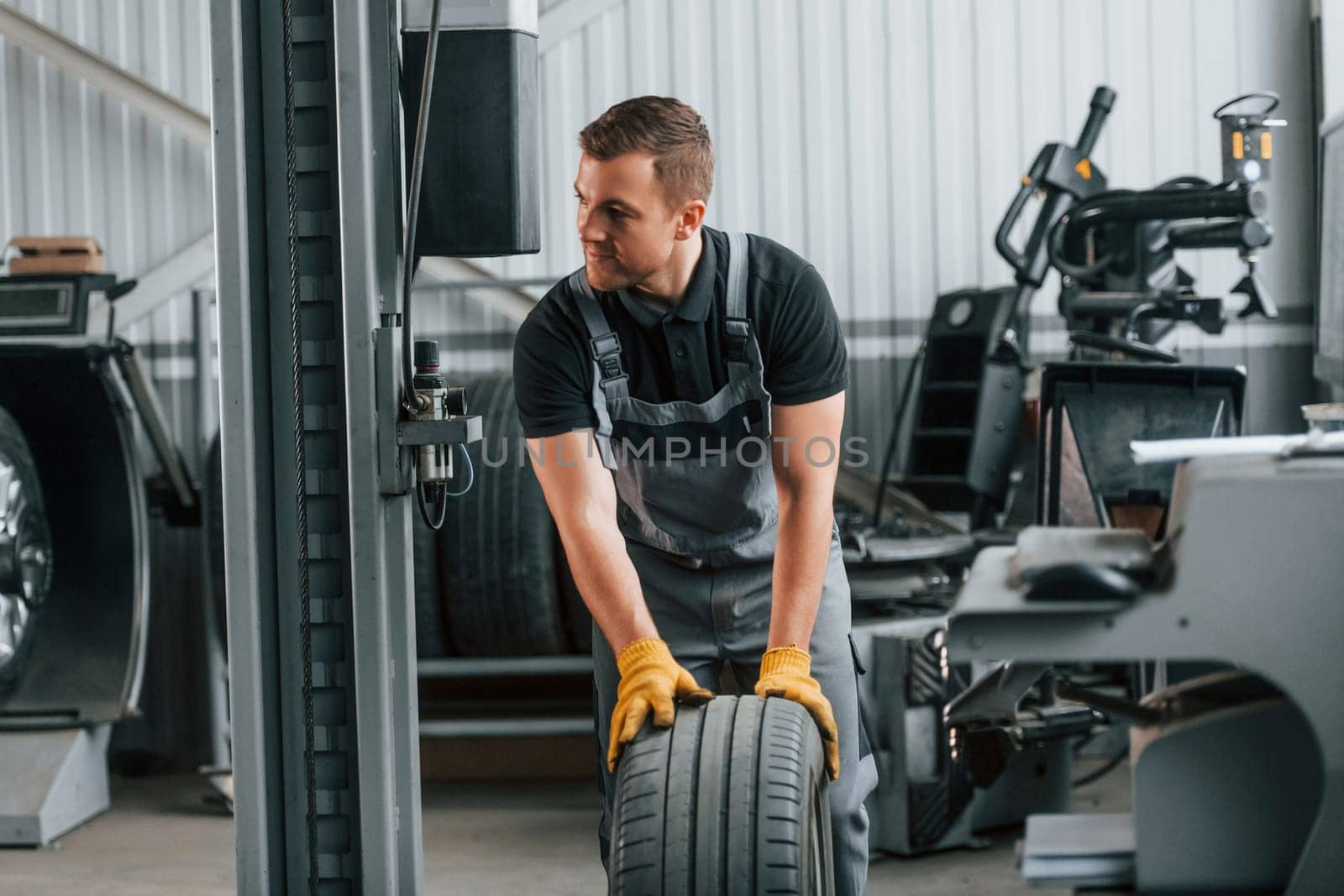 Front view. Man in uniform is working in the auto service.