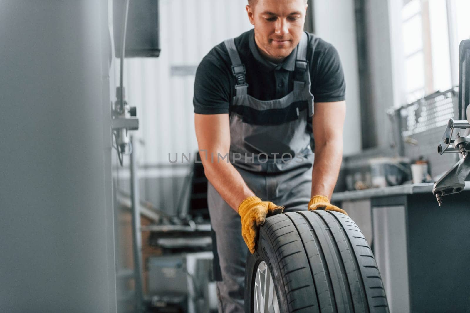 In black shirt. Man in uniform is working in the auto service.