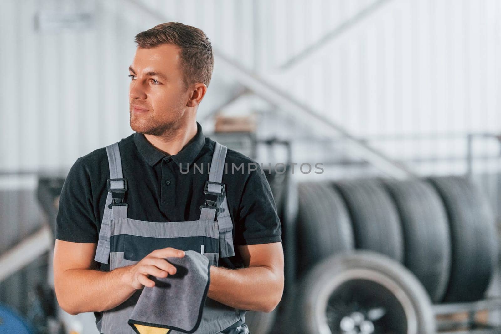 In black shirt. Man in uniform is working in the auto service by Standret