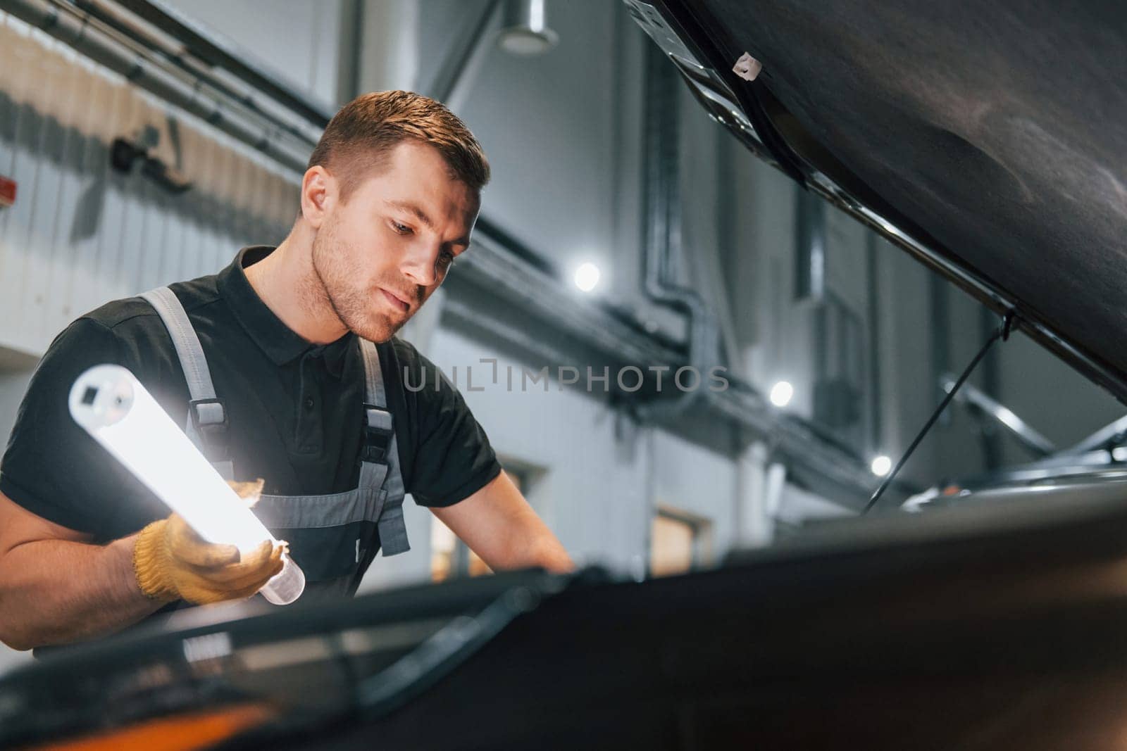 Ready to solve the problem. Man in uniform is working in the auto service.