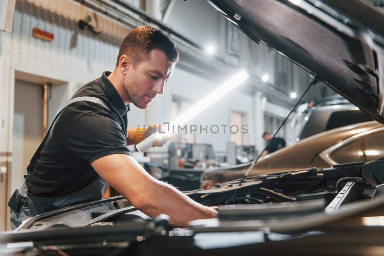 Ready to solve the problem. Man in uniform is working in the auto service.