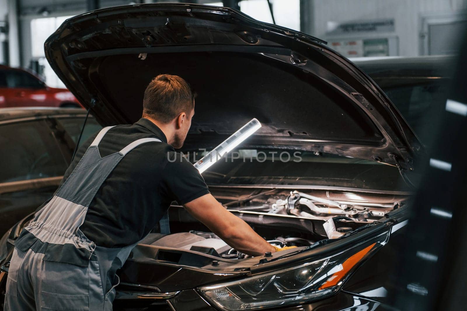 Side view. Man in uniform is working in the auto service by Standret