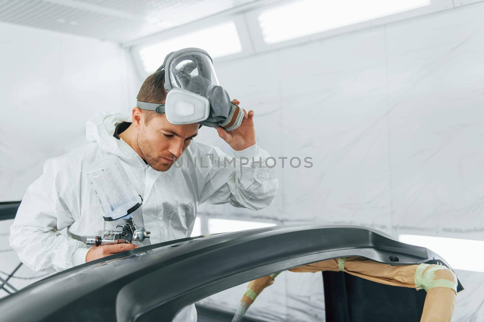 Working with car surface. Man in uniform is working in the auto service.