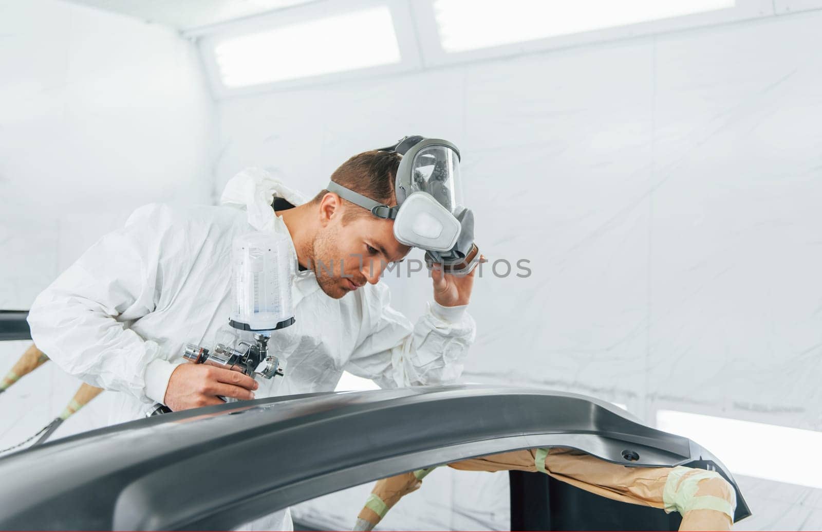 Working with car surface. Man in uniform is working in the auto service.