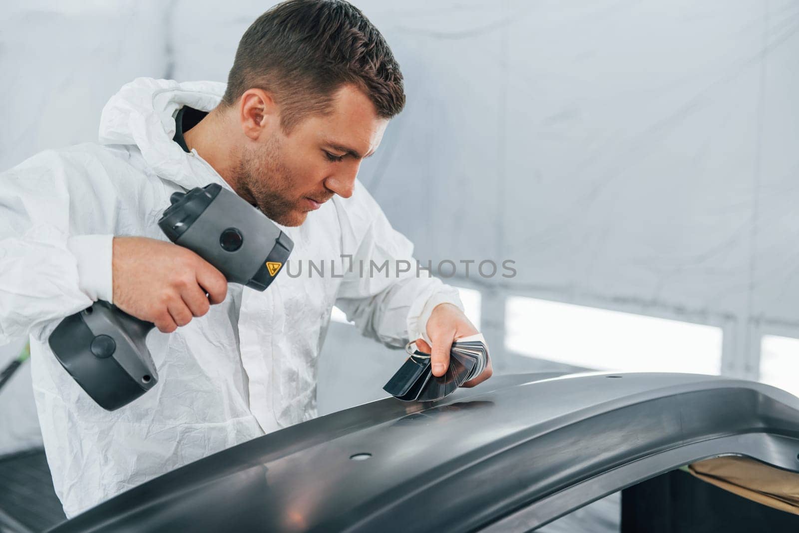 Working with car surface. Man in uniform is working in the auto service.
