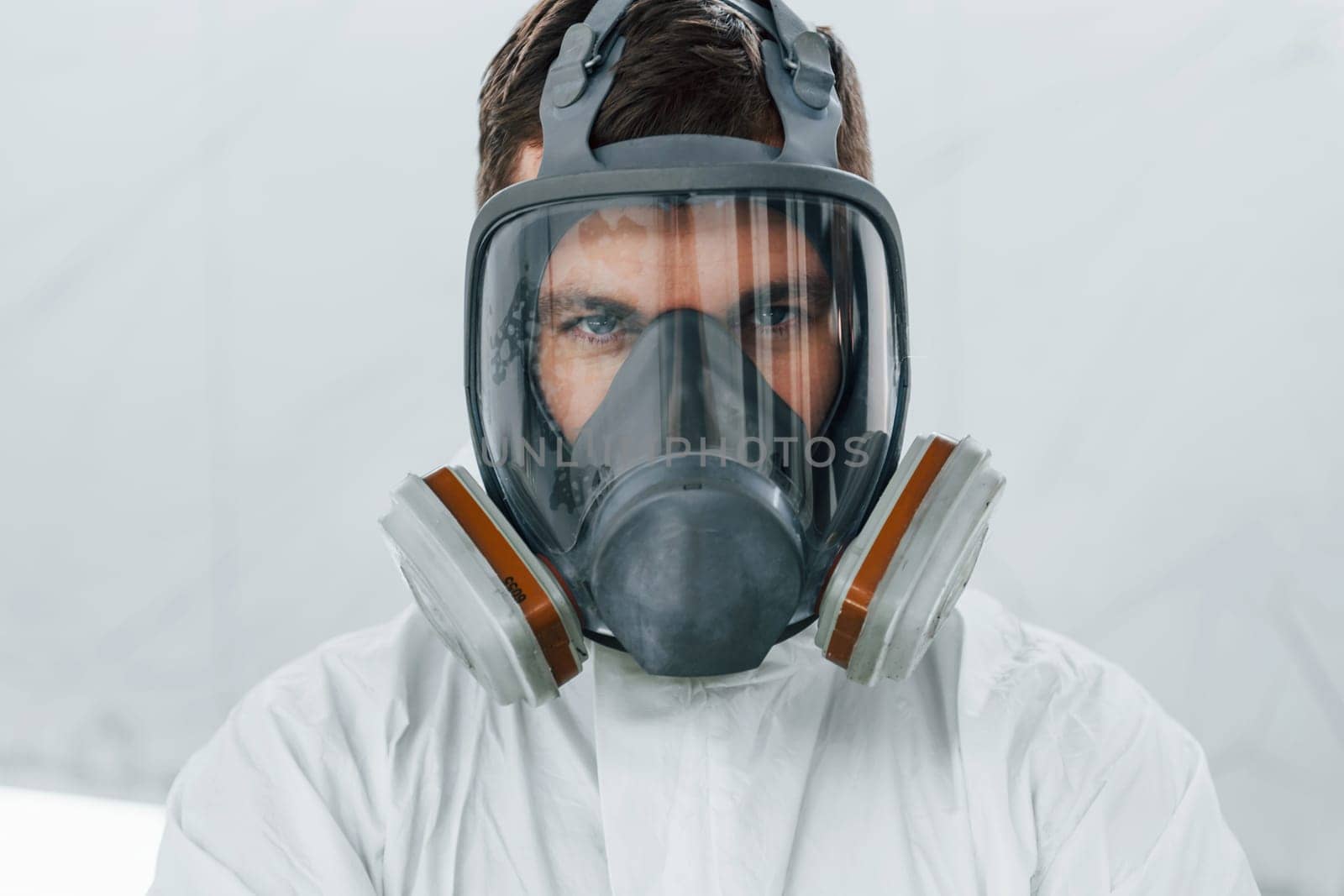 Portrait of man in the protective mask. Worker in uniform is in the auto service.