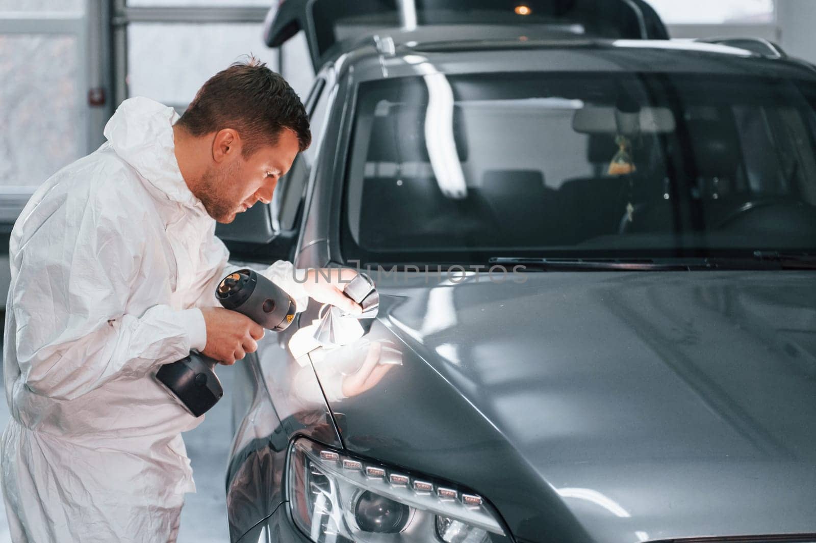 Using special equipment. Man in uniform is working in the auto service.