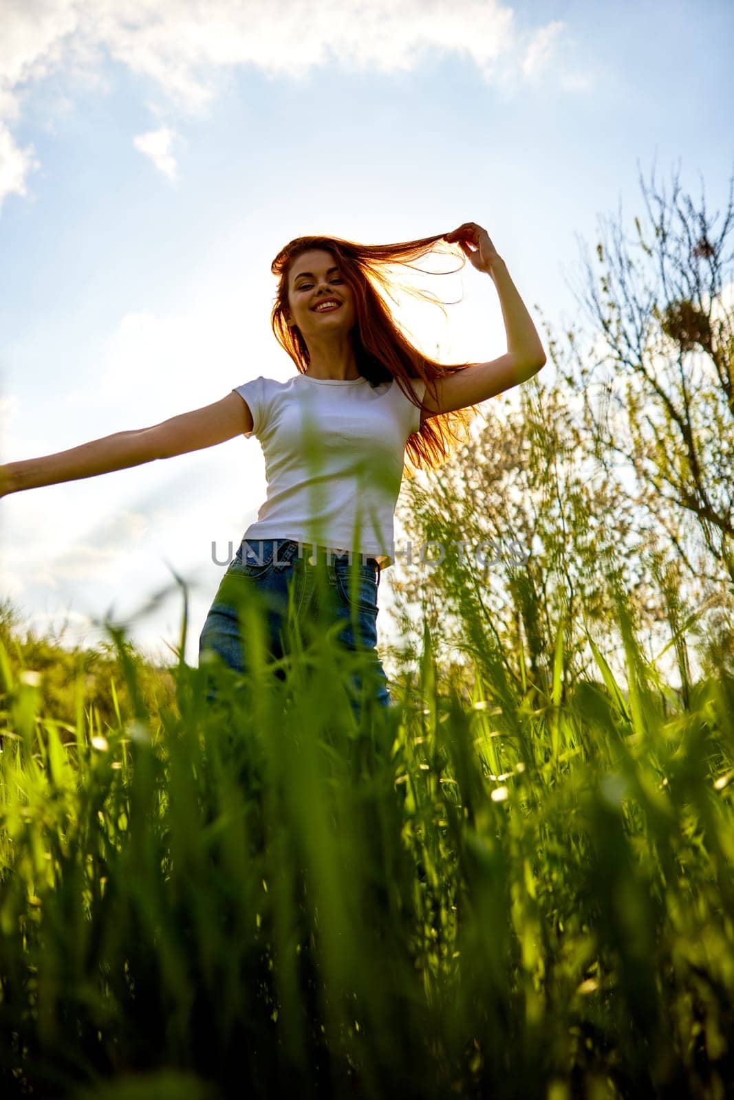 happy woman dancing in high grass field, bottom view. High quality photo