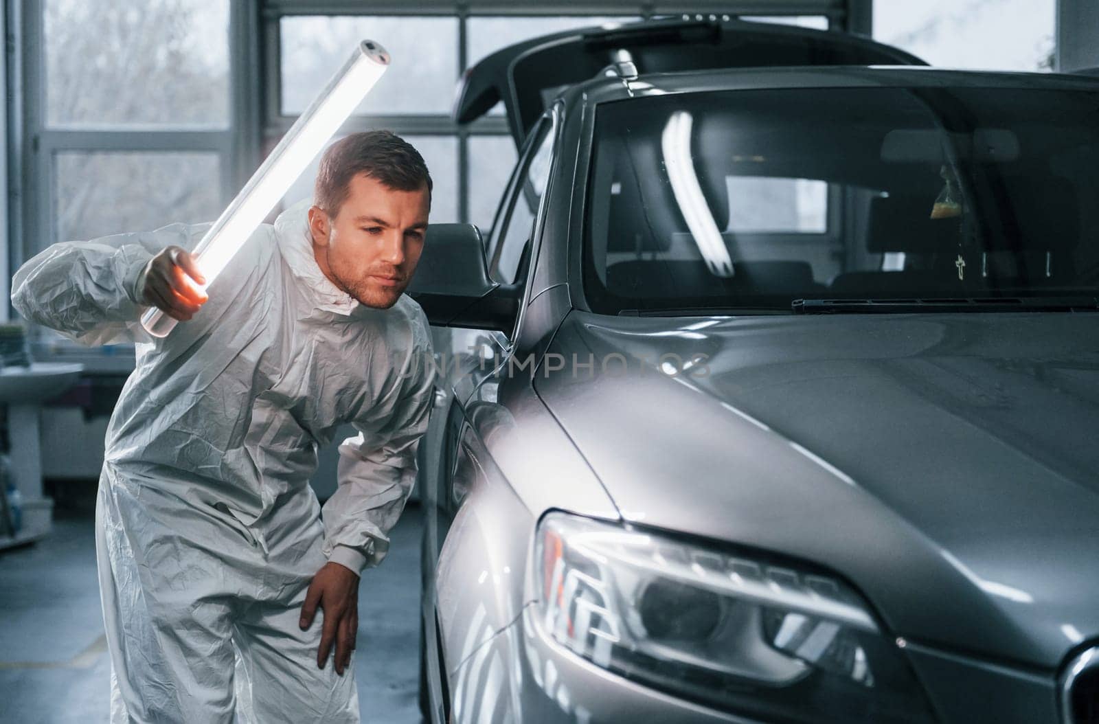 Silver colored car. Man in uniform is working in the auto service by Standret