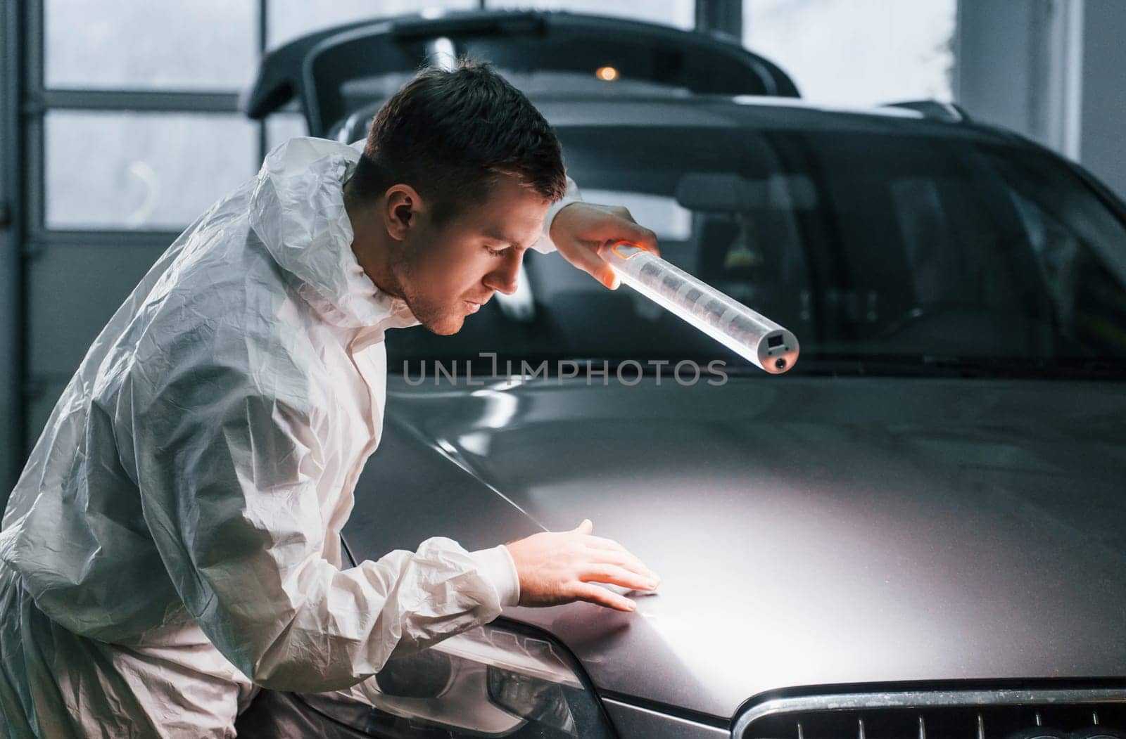 Silver colored car. Man in uniform is working in the auto service by Standret