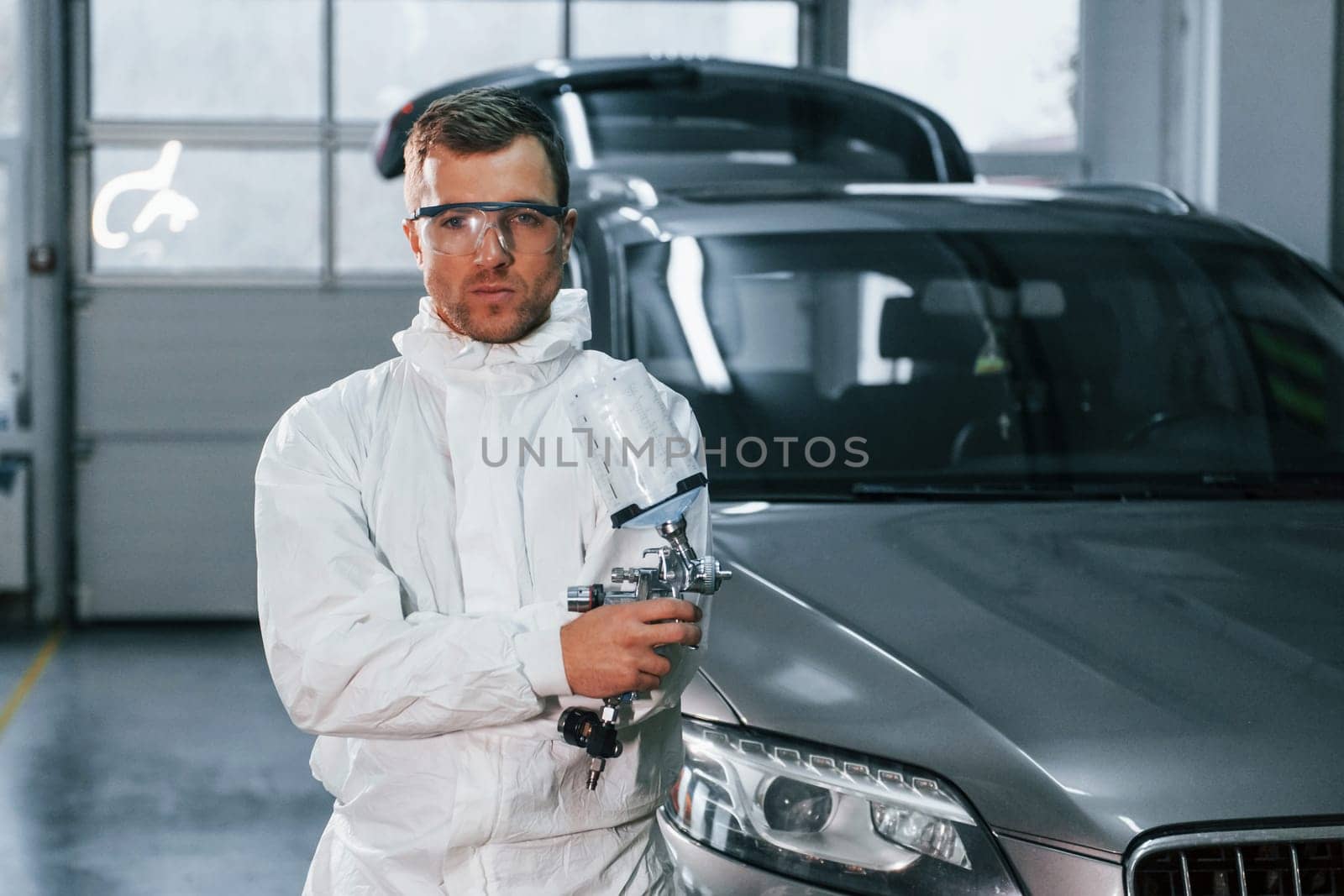 Process of painting the car. Man in uniform is working in the auto service.