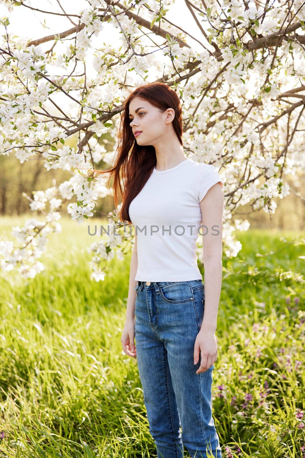 Beautiful young woman near blooming tree on spring day by Vichizh