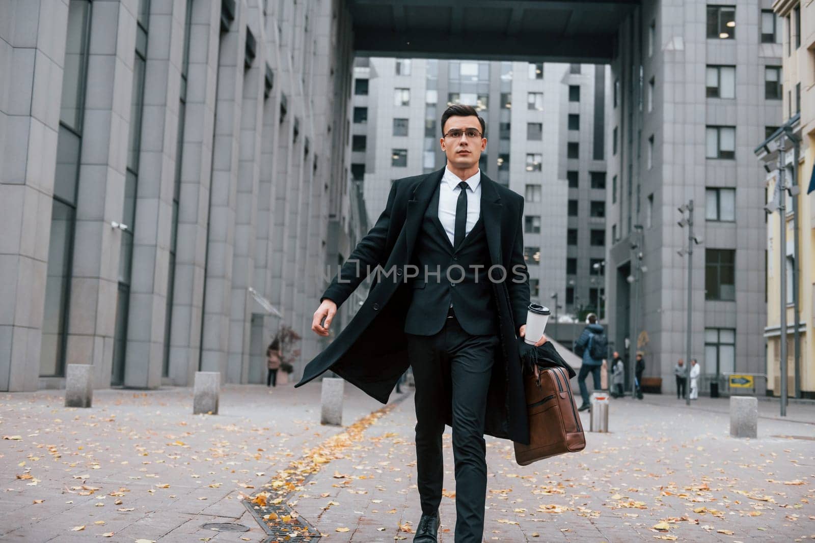 Going to work. Businessman in black suit and tie is outdoors in the city by Standret