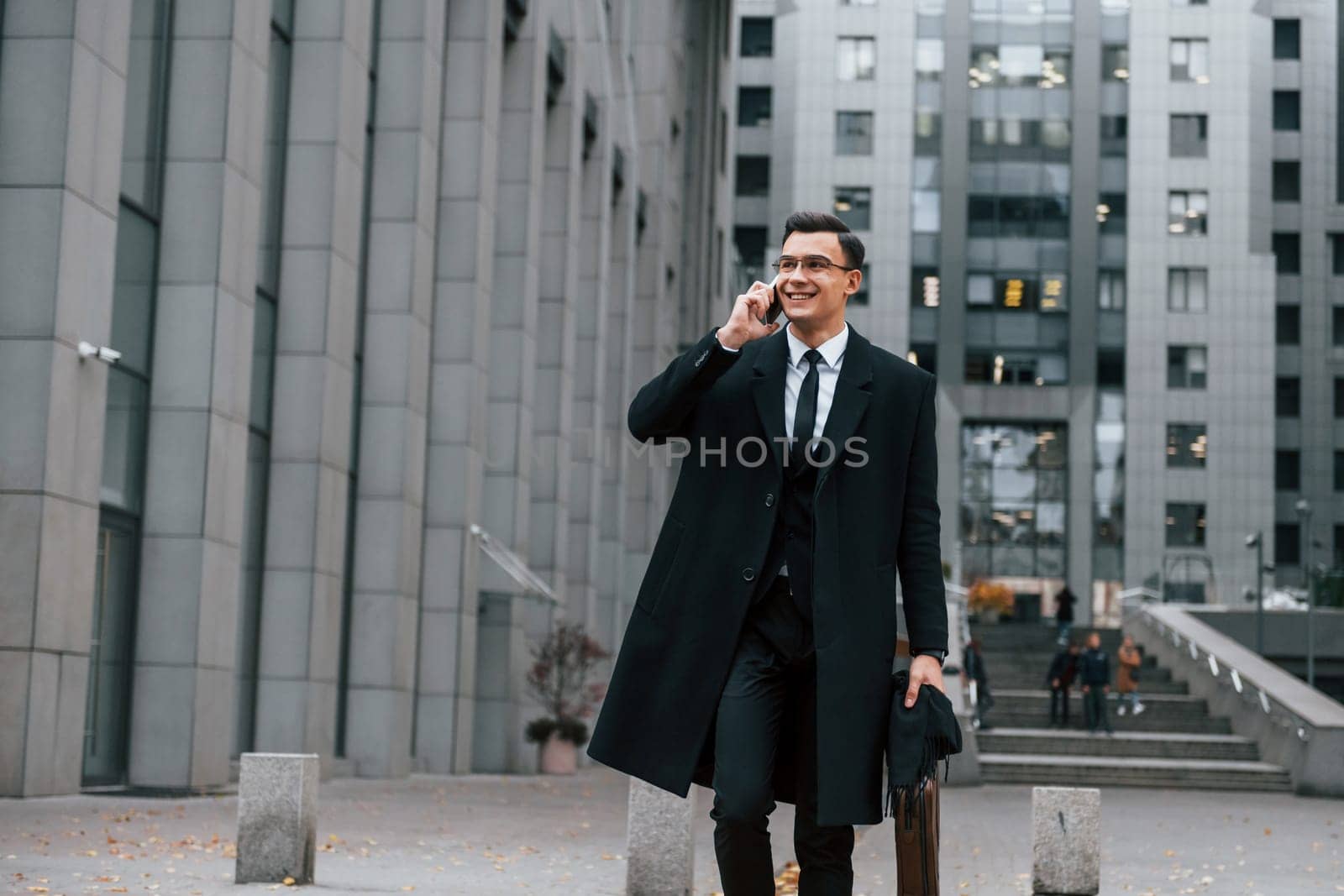 In formal clothes. Businessman in black suit and tie is outdoors in the city by Standret