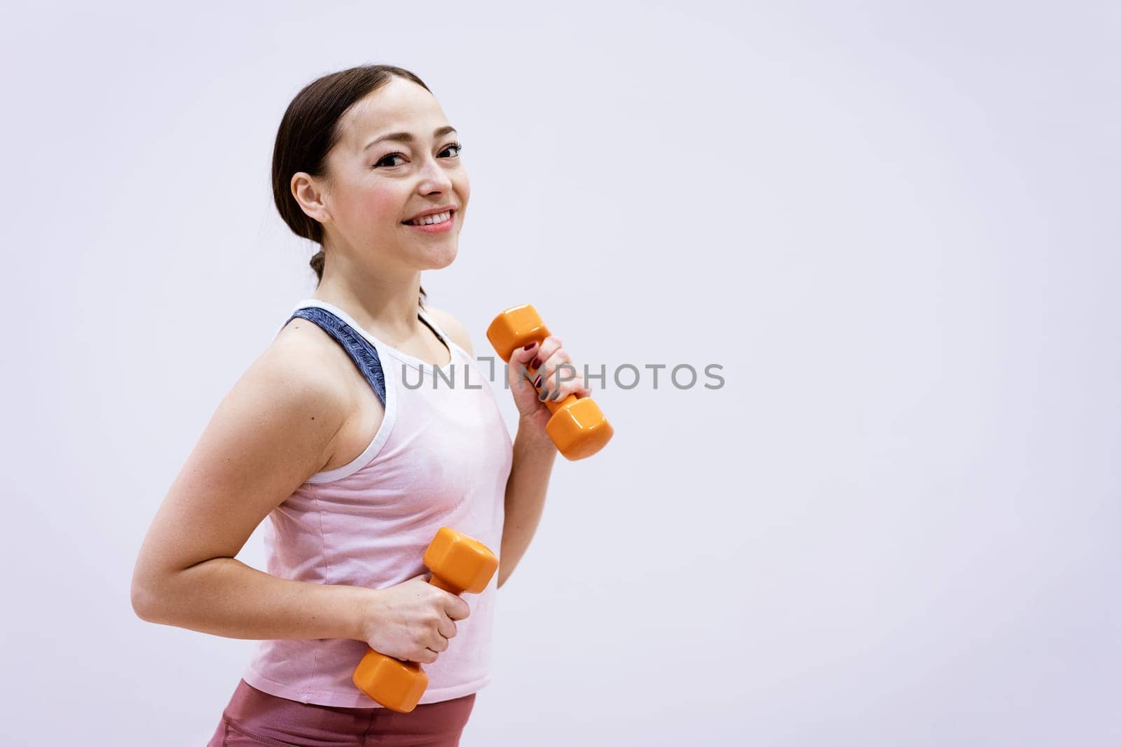 Woman in sportswear is engaged with dumbbells by EkaterinaPereslavtseva