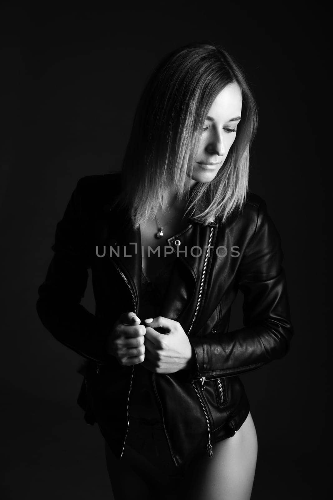 Portrait of a woman in a leather jacket and lingerie, black and white photo. Beautiful caucasian woman of nationality sensitive portrait on black background