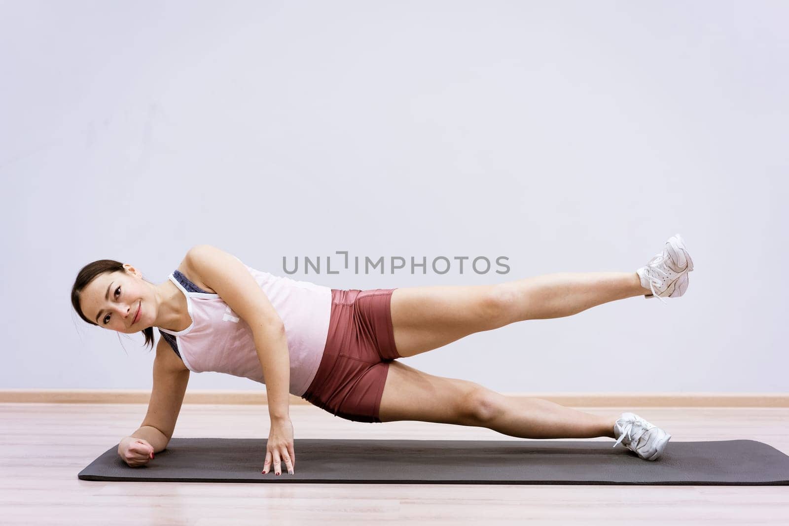 Happy caucasian woman in sportswear practices yoga at home against a wall background. The concept of a healthy lifestyle and inner spirit. Body concentration