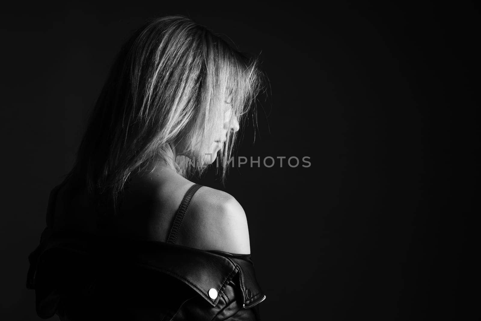 Portrait of a woman in a leather jacket and lingerie, black and white photo. Beautiful caucasian woman of nationality sensitive portrait on black background