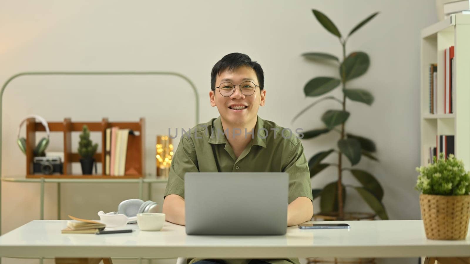 Smiling millennial man working on laptop or using internet banking service. People, technology and lifestyle concept.